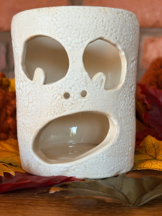 Handmade crackle‑glazed ceramic ghost tea light holder with hollow eyes and warm autumn styling.